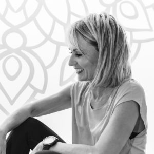 portrait_72dpi Portrait de profil de josiane buchart souriant avec en fond le logo orchidée du studio pilates yoga de satigny